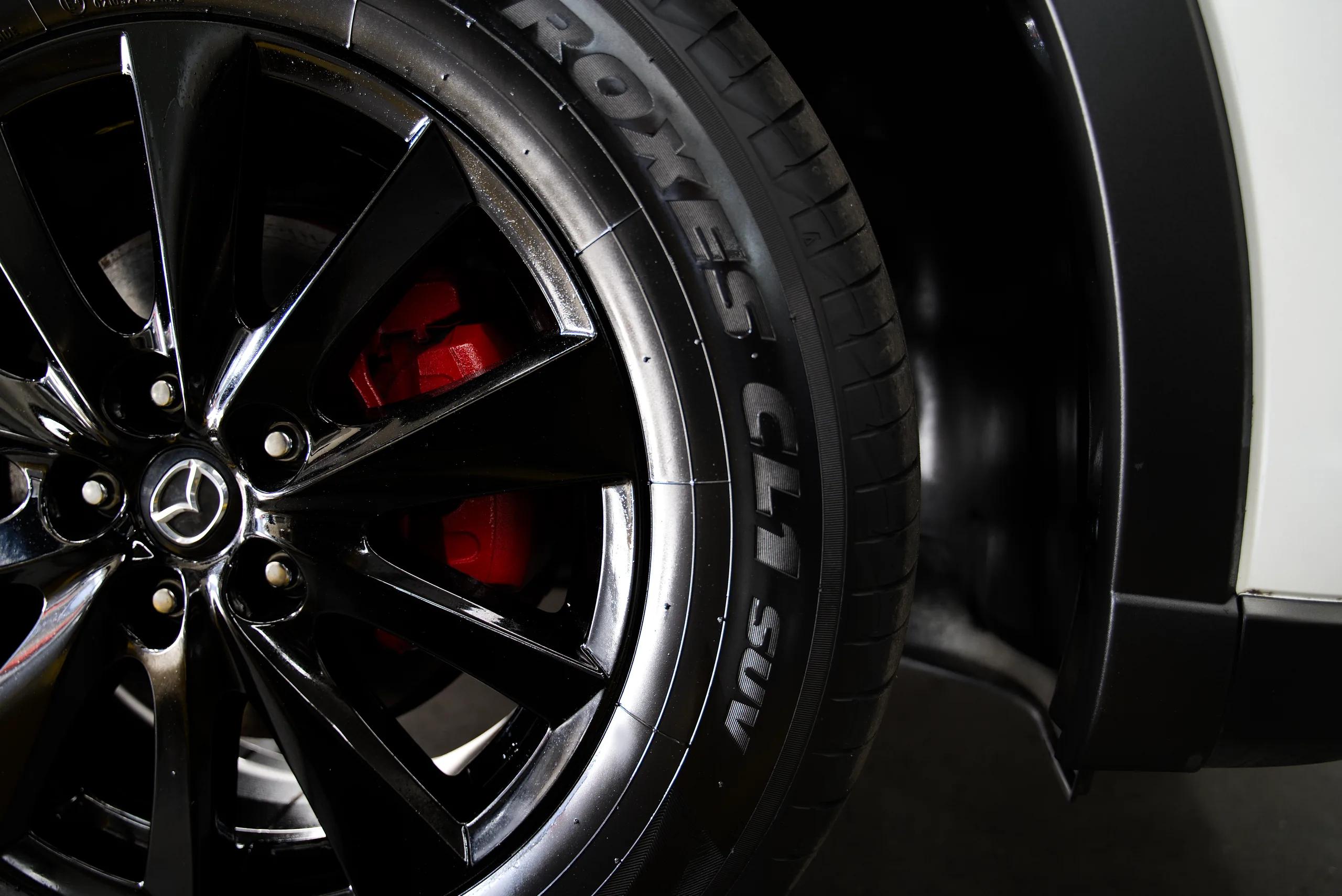 A Mazda wheel and tyre with a red brake caliper behind the spokes